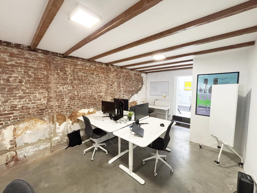 Modern office workspace on Van Ostadestraat with exposed brick wall and minimalist furniture.